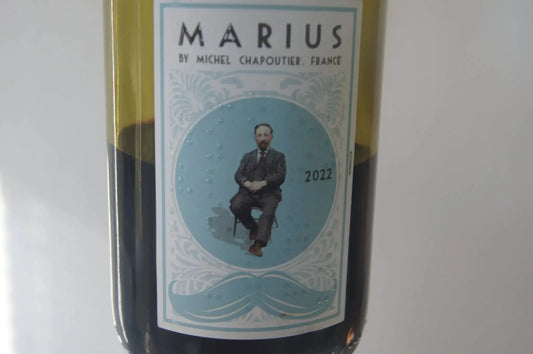 Ein Glas Marius 2022, ein repräsentativer Rotwein aus Südfrankreich, serviert bei optimaler Temperatur, zeigt seine leuchtende purpurrote Farbe und die tiefe Qualität seiner Tannine."